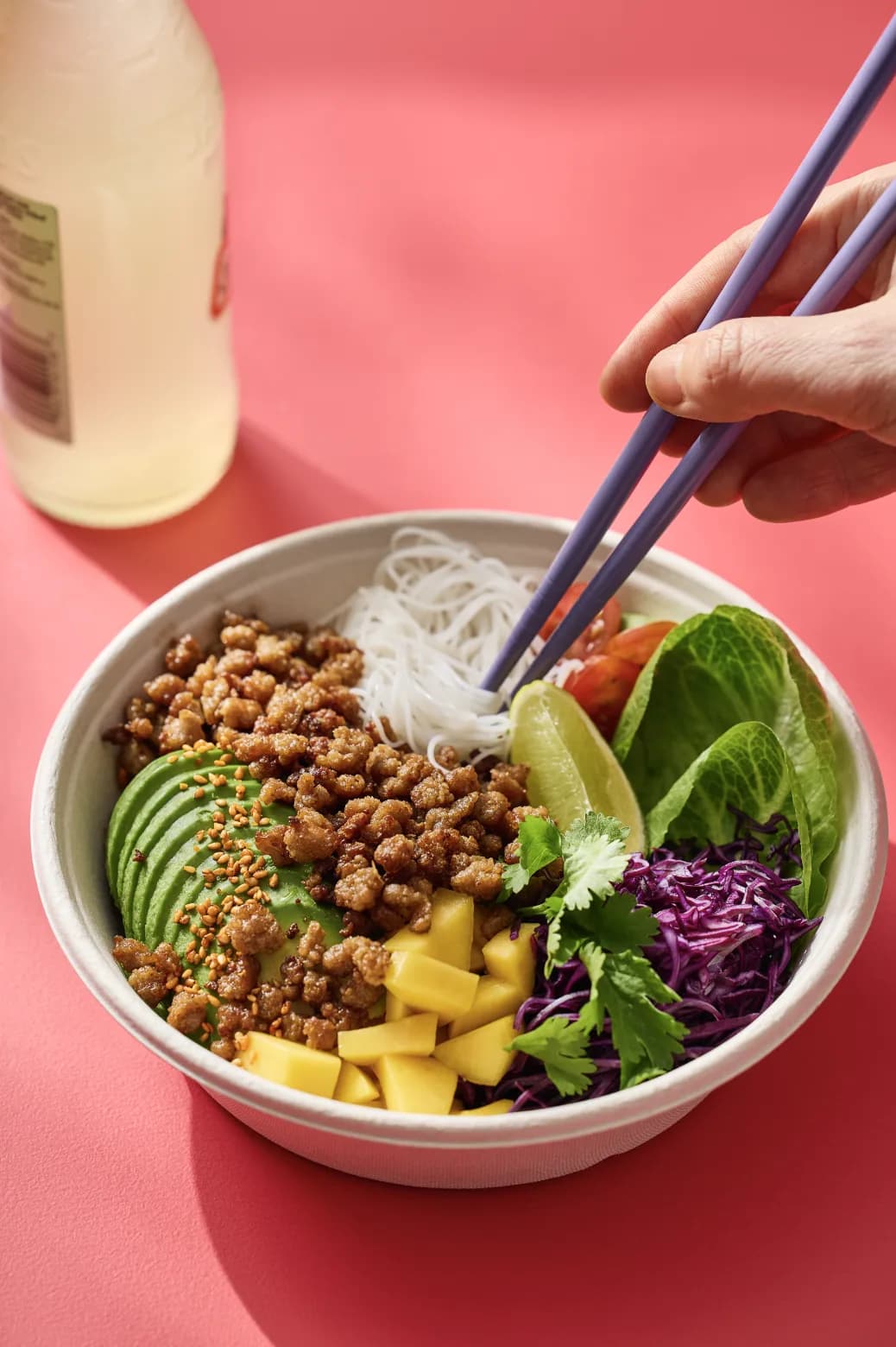 Bowl of Millow mince with avocado, mango and fresh vegetables, eaten with chopsticks